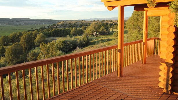 A wooden deck with a railing overlooking a scenic landscape. - Wranglers Quarters RiverView Cabin - Sevier River Ranch - 1 King bed (Hatch)