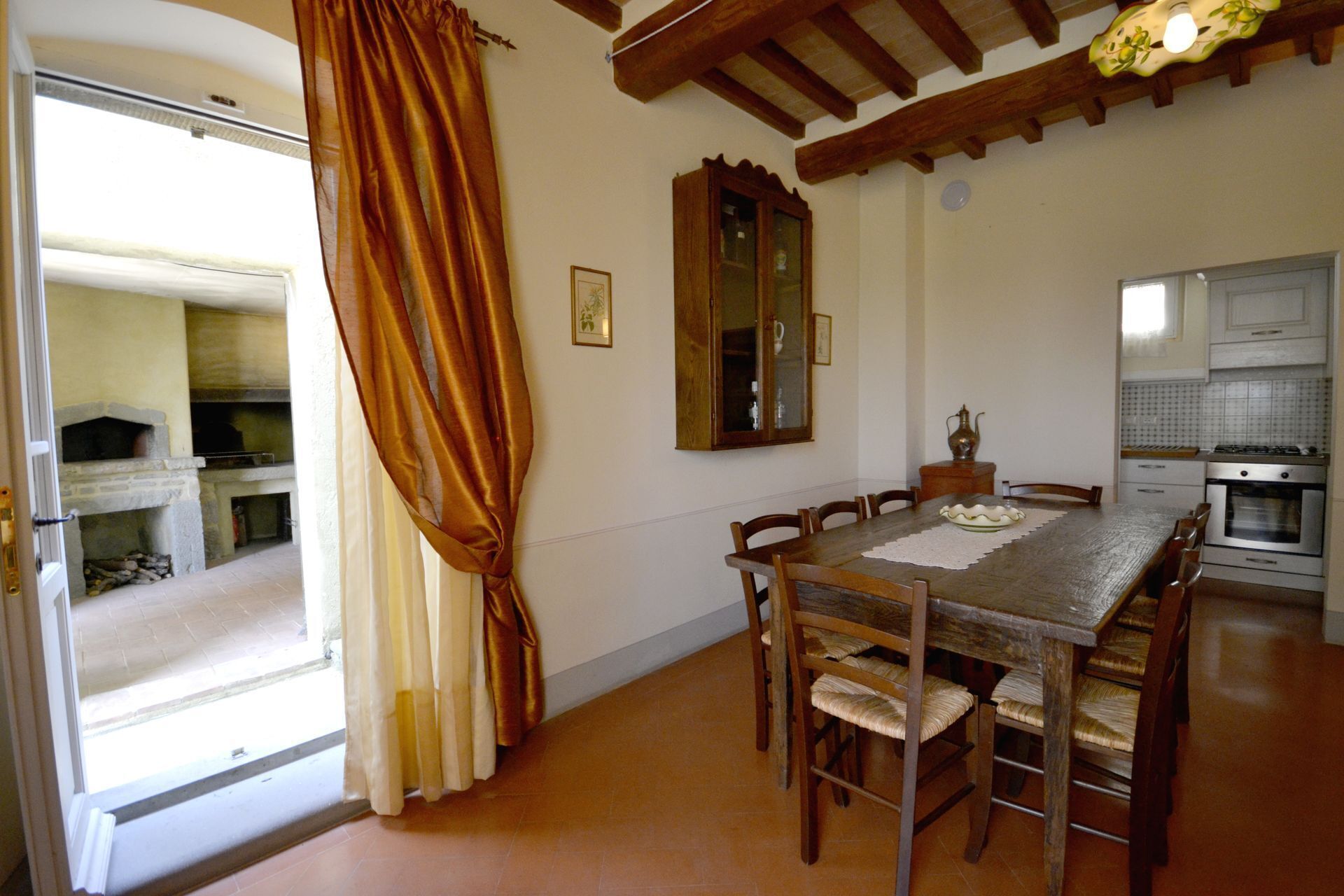 A dining area with a wooden table and chairs, a kitchen with modern appliances, and a fireplace.