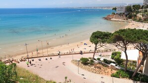 Une plage avec une promenade dallée, quelques personnes et des bâtiments en arrière-plan.