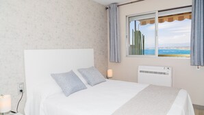 Une chambre à coucher avec un lit, une fenêtre donnant sur la mer et un climatiseur fixé au mur.