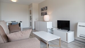 Un salon moderne comprenant un canapé, une table basse, un téléviseur et un petit meuble.