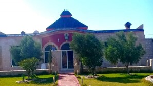 A building with a red facade, a blue dome, and a pathway leading to the entrance. - Charming villa with pool 4160 (Essaouira)