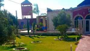 A courtyard with a gazebo, a water tower, and a building with arched windows. - Charming villa with pool 4160 (Essaouira)