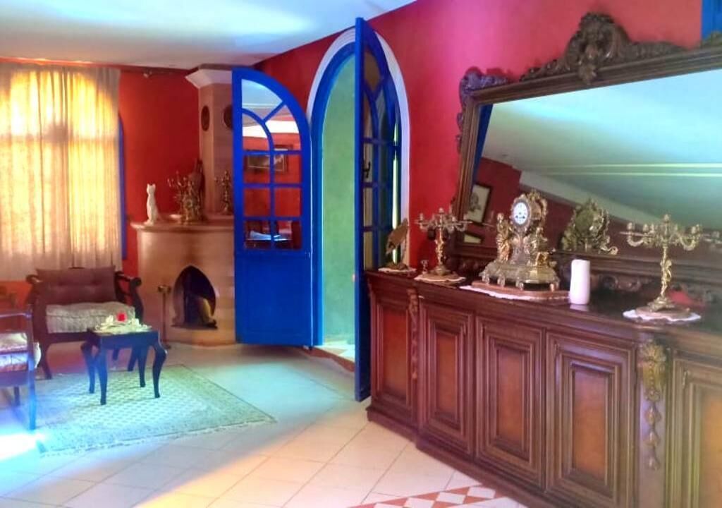 A room with a fireplace, a wooden cabinet with decorative items, and a large mirror.