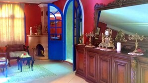 A room with a fireplace, a wooden cabinet with decorative items, and a large mirror. - Charming villa with pool 4160 (Essaouira)