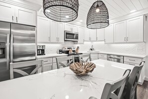 A modern kitchen with white cabinetry, stainless steel appliances, and a marble countertop. - Tropical Garden View 2 bed, 2 bath at Sanibel Moorings #932 (Sanibel)