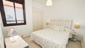 Une chambre à coucher avec un lit, des lampes de chevet, une table de chevet, une fenêtre et une armoire.