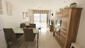 Une cuisine moderne avec un coin repas, des meubles en bois et un téléviseur.