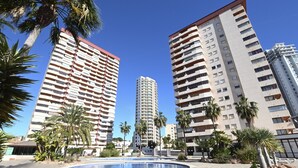 Un hôtel de grande hauteur, avec de nombreux étages, une cour intérieure dotée d’une piscine et entourée de palmiers.