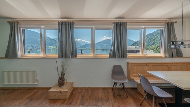 Una habitación con un ventanal grande, suelo de madera, una mesa de comedor y un banco.