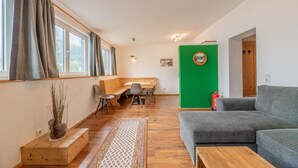Una sala moderna con un sofá gris, una mesa de centro de madera y un comedor con banco y sillas.