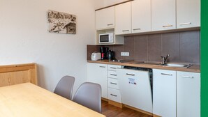 Una cocina compacta con armarios blancos, microondas, tostadora y lavavajillas.