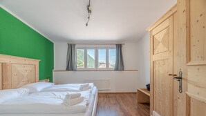 Una habitación con cama, ventana con cortinas, armario de madera y radiador.
