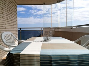 A balcony with a table and chairs, a glass partition, and a view of the sky and clouds. - A66 BAHIA DEL SOL 13A (Calpe)