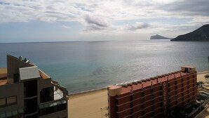 A coastal hotel with a view of the sea and a distant mountain.