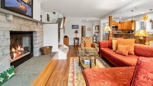 Ein geräumiges Wohnzimmer mit Kamin, einem roten Sofa und einer Küchenzeile im Hintergrund.