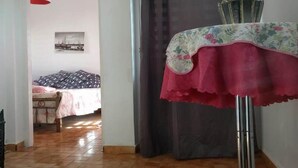 Ein Zimmer mit einem Bett, einem Tisch mit blumigem Tischläufer und einem Fenster mit Blick auf Boote.