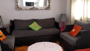 Ein Wohnzimmer mit einem grauen Sofa, einem runden weißen Tisch und zwei Lampen.