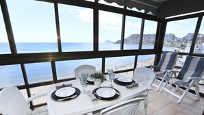 Área de refeições com mesa posta para quatro, com vista para a praia.