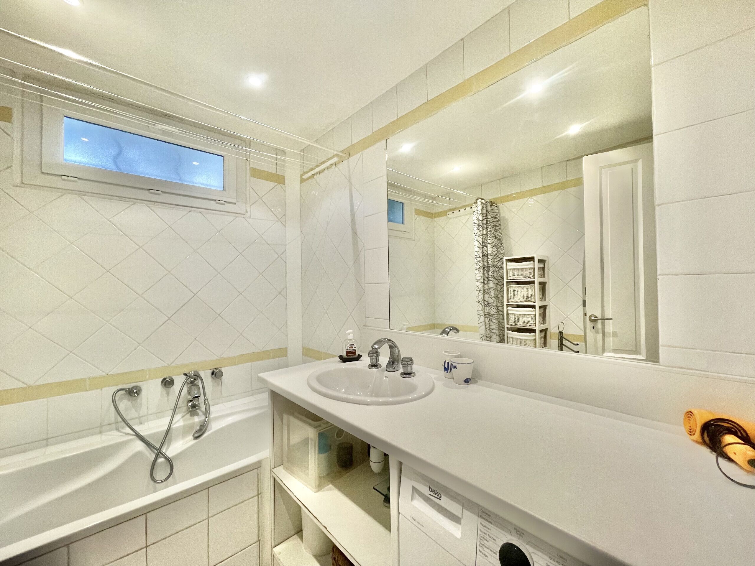 Un bagno moderno con uno specchio grande, una vasca e un lavandino.