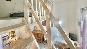 A multi-level interior with a wooden staircase, a television, and a desk area. - Villa Marjolette (Cannes)