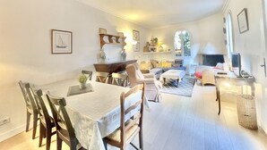 A spacious living room with a dining area, a fireplace, and a large window providing natural light. - Villa Marjolette (Cannes)