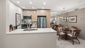 A modern kitchen with a central island, stainless steel appliances, and a dining area with wicker chairs. - Cozy Garden View 1 bed, 1 bath at Sanibel Moorings #912 (Sanibel)