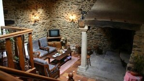 Ein Wohnzimmer mit Steinwänden, einem Kamin, Holzmöbeln und zwei Wandleuchten.