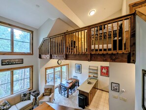 A multi-level room with a loft bed, a dining area, and a kitchen.
