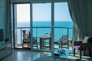 Un balcon avec une table et des chaises, un canapé et un téléviseur.