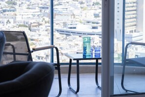 Un balcón con una mesa, sillas y vista a un paisaje urbano.
