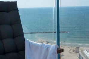 Vista de una playa desde una ventana, con una silla y una toalla.