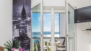 A modern living room with a sofa, a coffee table, and a TV. A balcony with a glass door leads to an outdoor seating area with a table and chairs. - Apartment in Crikvenica with Seaview, Terrace, Air condition, WIFI (3492-6) (Crikvenica)