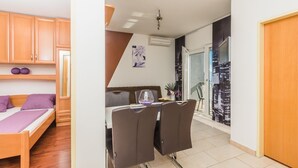 A compact living space with a bed, a dining area with two chairs, a small table, and a cityscape view through a glass door. - Apartment in Crikvenica with Seaview, Terrace, Air condition, WIFI (3492-6) (Crikvenica)
