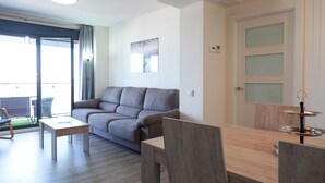 Una sala moderna con un sofá gris, una mesita de madera y una mesa de comedor con sillas.