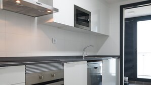 Una cocina moderna con armarios blancos, horno empotrado y lavavajillas.