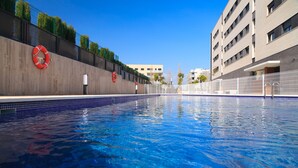 Una piscina con boyas salvavidas en la pared, rodeada de edificios.