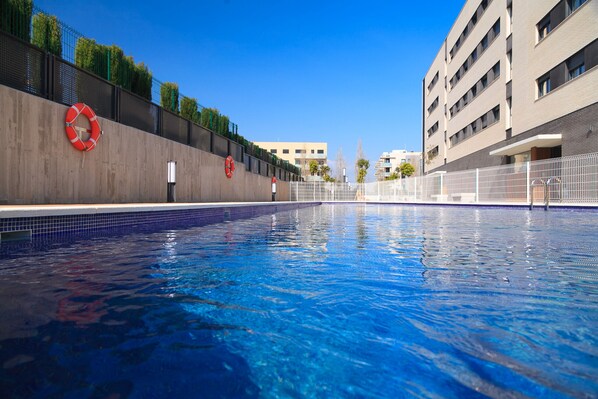 A swimming pool with lifebuoys on the wall, surrounded by buildings.