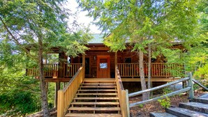 A wooden cabin with a stone staircase leading to a wooden deck. - New Hot Tub, Beautiful Cabin, Resort Pool, Putt Putt, Golf, 5mi to Pigeon Forge (Sevierville)