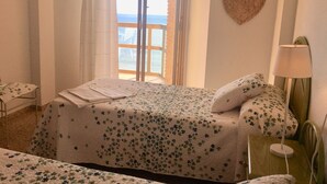 A bedroom with a bed, a bedside table with a lamp, a window with a view of the sea, and a heart-shaped decoration on the wall. - A47 CALPEMAR C 5º 19 (Calpe)
