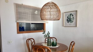 A dining area with a round wooden table, four chairs, a woven pendant light, a window with blinds, and a framed botanical print on the wall. - A47 CALPEMAR C 5º 19 (Calpe)