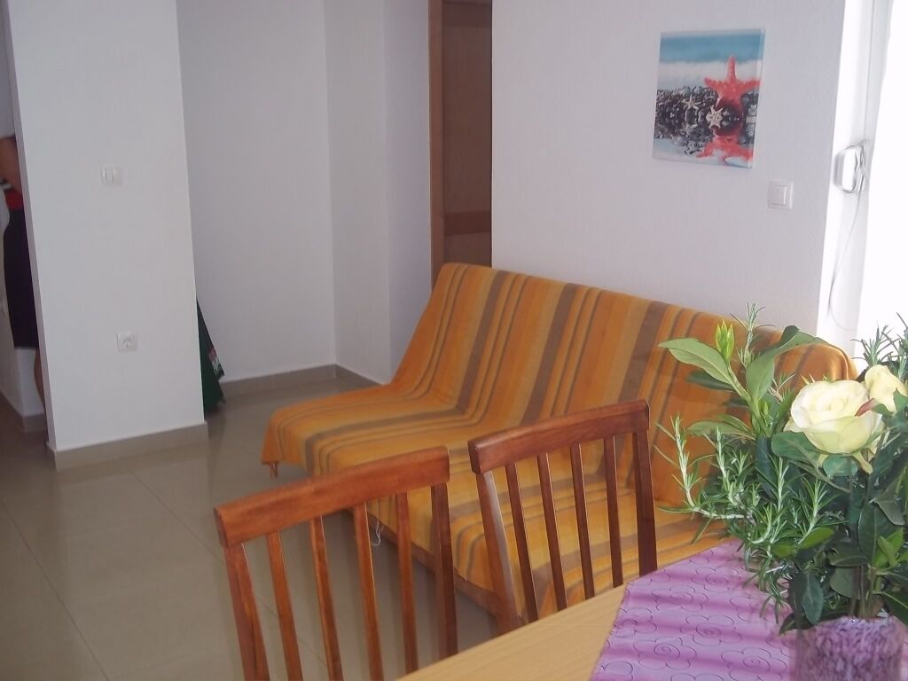 A dining area with a wooden table, chairs, and a vase with flowers.