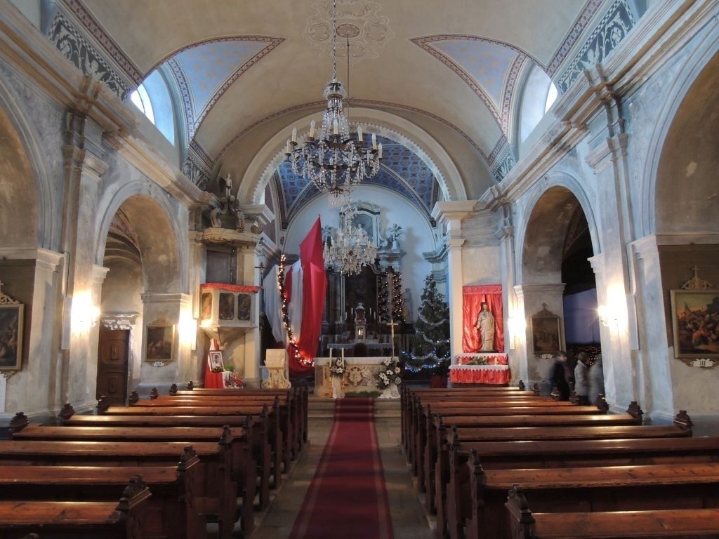 An interior of a church with wooden pews, a central altar, and a chandelier.