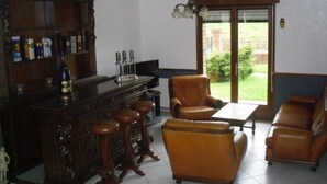 Ein Wohnzimmer mit einer Holztrennwand, Ledersesseln und Blick ins Freie.