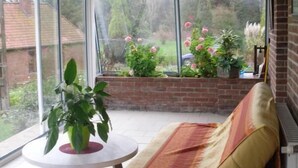 Ein Wintergarten mit einem gelben Sofa, einem runden Tisch und einer Topfpflanze.