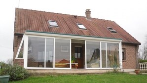 Ein Haus mit großem Wintergarten, Ziegelaußenwand und einem Ziegeldach.
