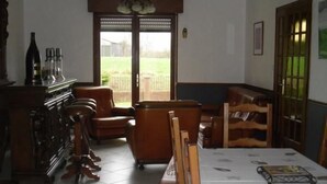 Ein Essbereich mit Tisch für vier Personen, einer Holzbank und Blick auf einen Garten durch eine Glastür.