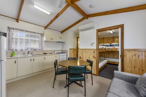 Una cocina compacta con comedor, vigas de madera y camas literas.