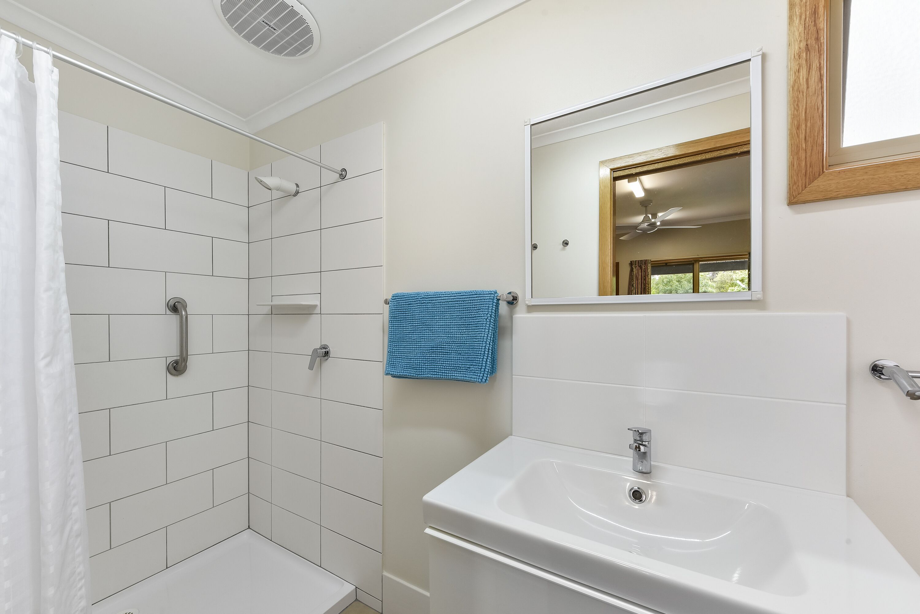A bathroom with a shower, a sink, and a mirror.