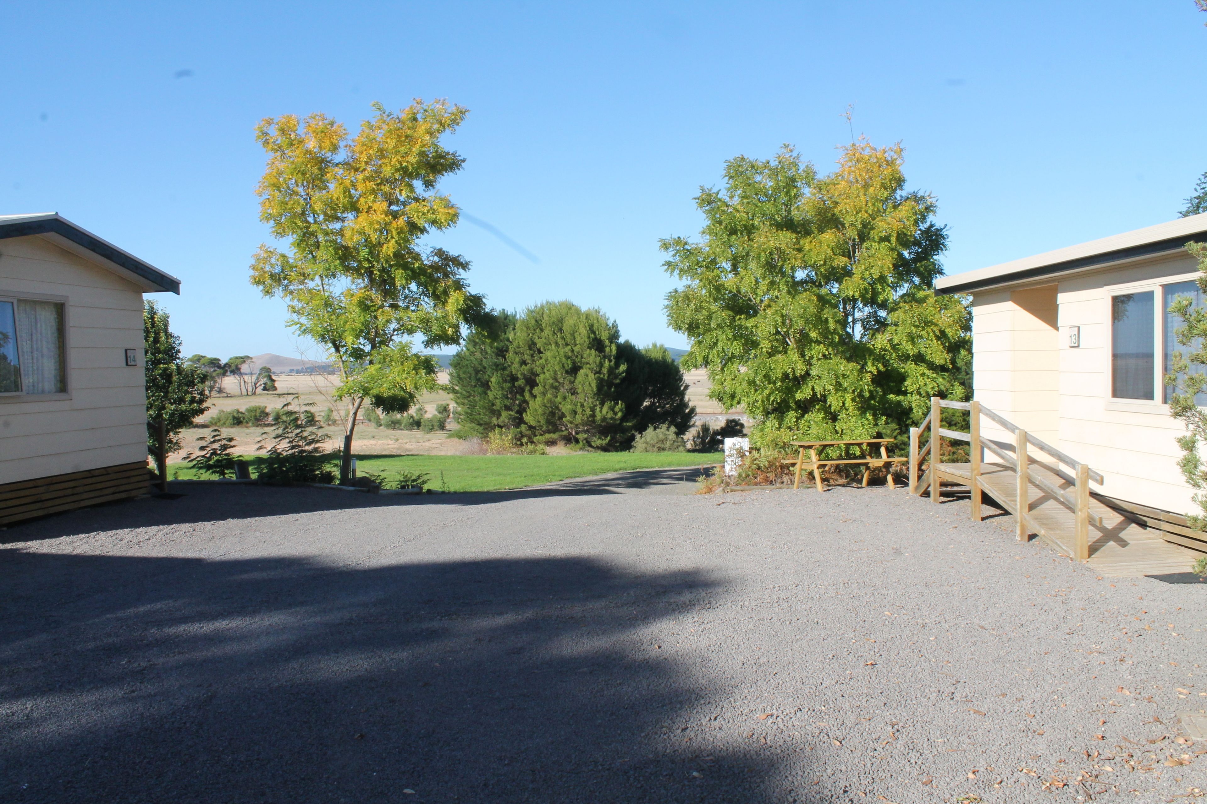 A gravel driveway leading to a wooden bridge connecting two mobile homes.